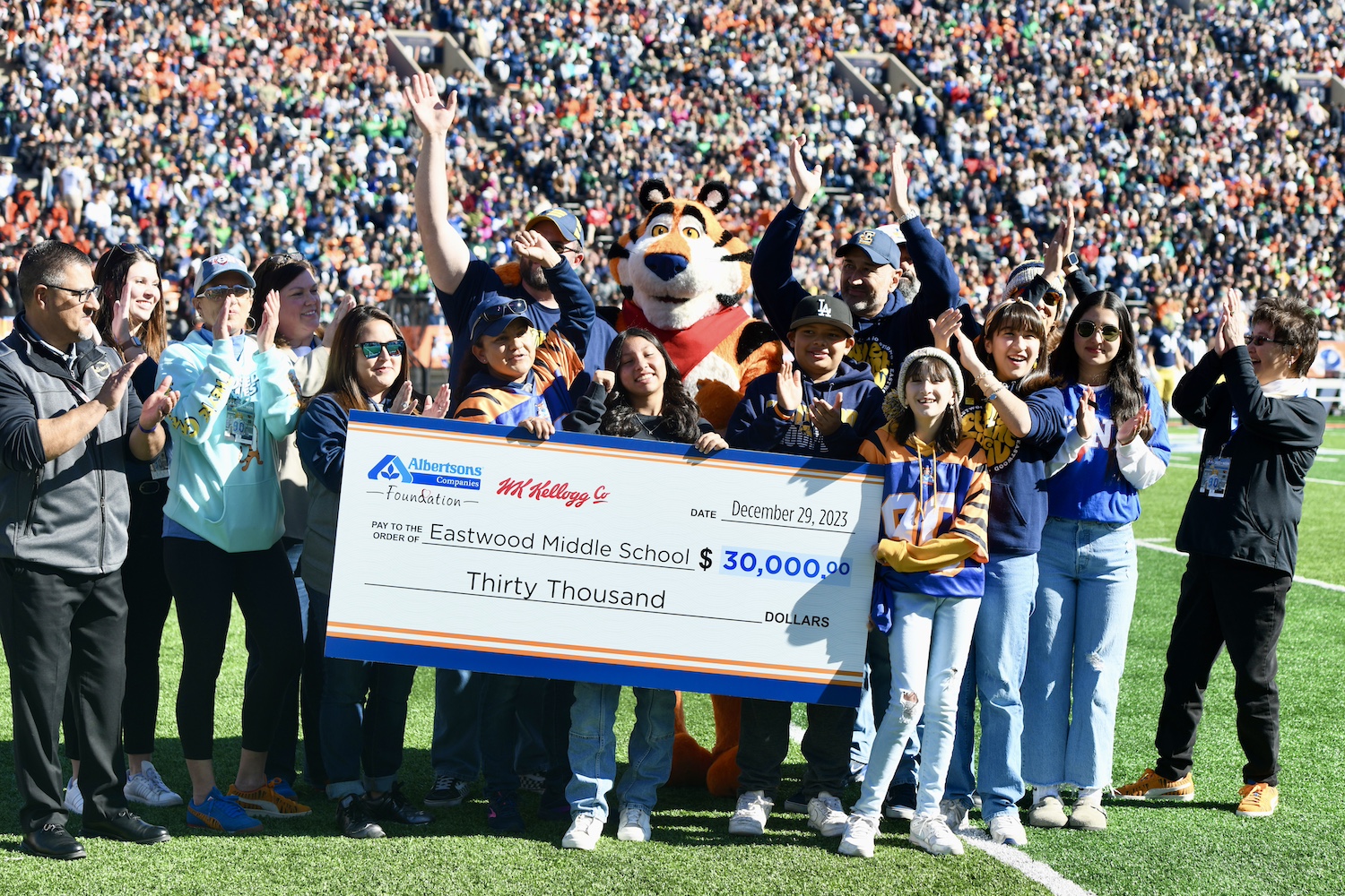 Tony the Tiger holds a check that will be used to support a middle school sports program as a part of Mission Tiger.